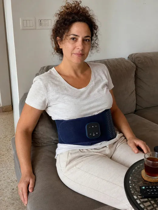 קרן יושבת על הספה עם חגורת BackPro